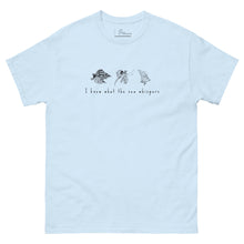 Load image into Gallery viewer, Light blue t-shirt featuring minimalist line drawings of clams (achivades) and sea snails, with the phrase &#39;I know what the sea whispers&#39; printed on the front.
